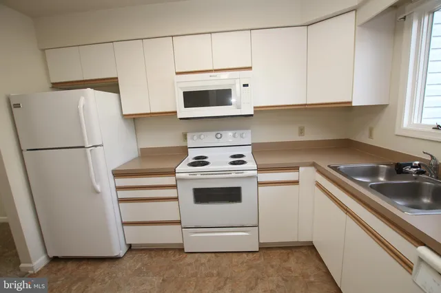 a kitchen with white cabinets and white appliances