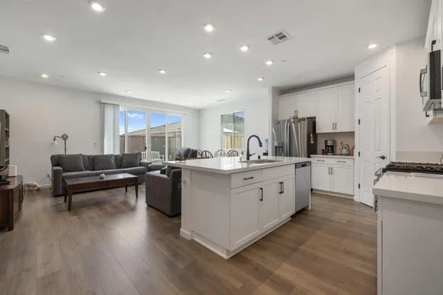 a kitchen with stainless steel appliances granite countertop a sink stove refrigerator and cabinets