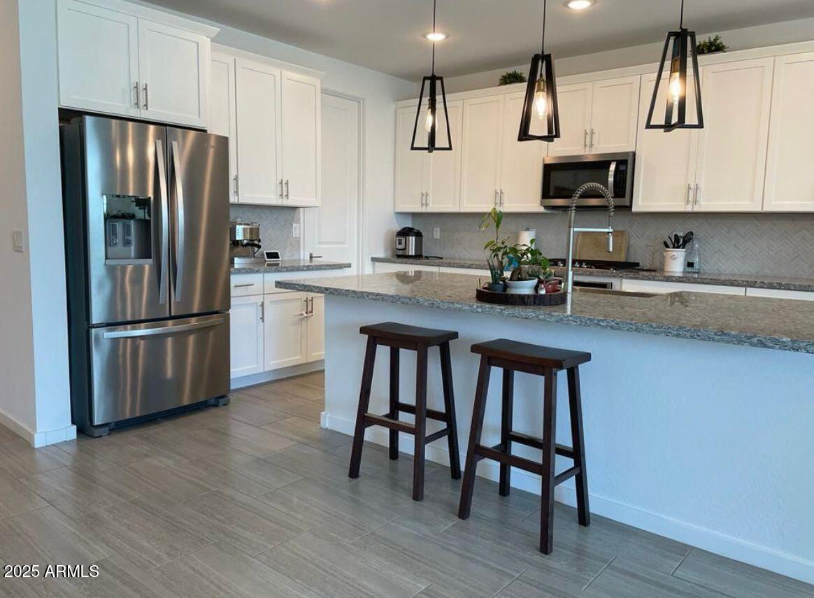 22547 East Quintero Road Queen Creek, AZ 85142 - Photo 1 of 17 a kitchen with stainless steel appliances a table chairs microwave and refrigerator