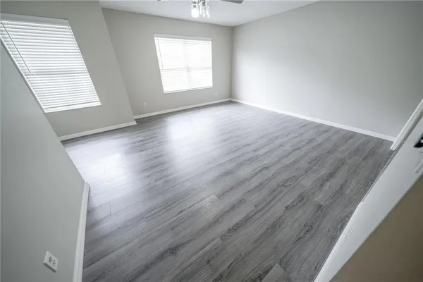 an empty room with wooden floor and windows