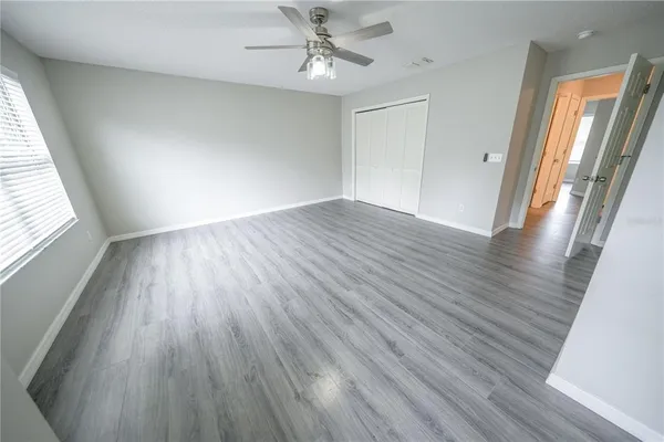 an empty room with wooden floor and windows