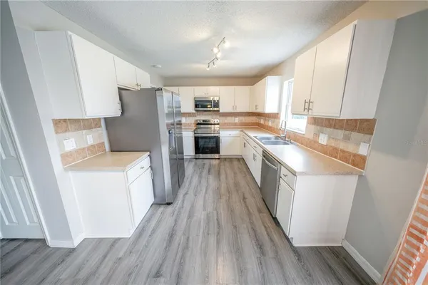 a kitchen with a sink a refrigerator a stove top oven and wooden floor