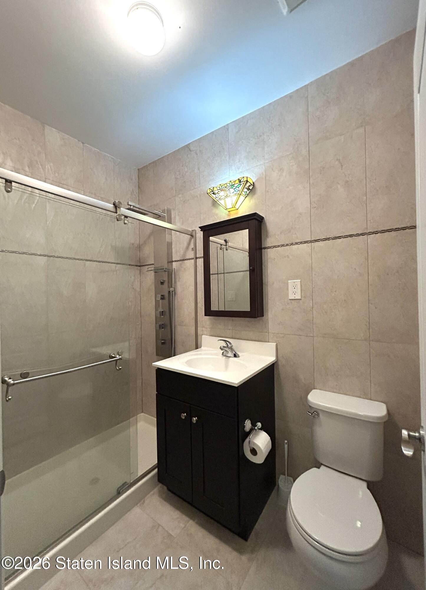 1235 Forest Hill Road, Unit 1G Staten Island, NY 10314 - Photo 11 of 11 a bathroom with a toilet a sink and mirror