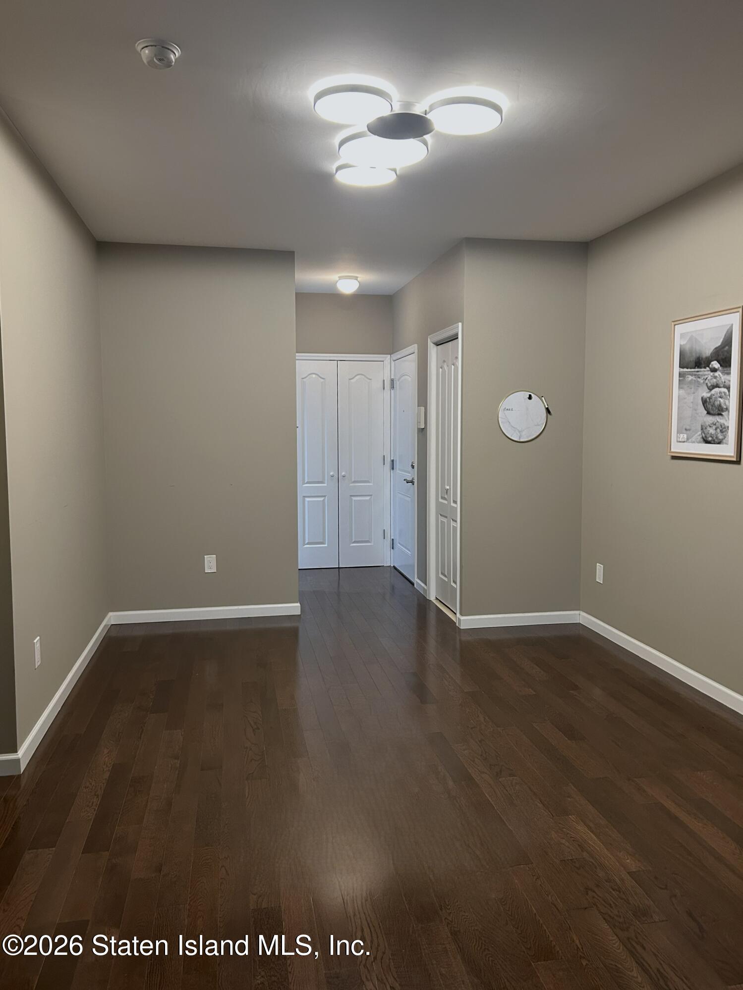 1235 Forest Hill Road, Unit 1G Staten Island, NY 10314 - Photo 3 of 11 an empty room with wooden floor and ceiling fan