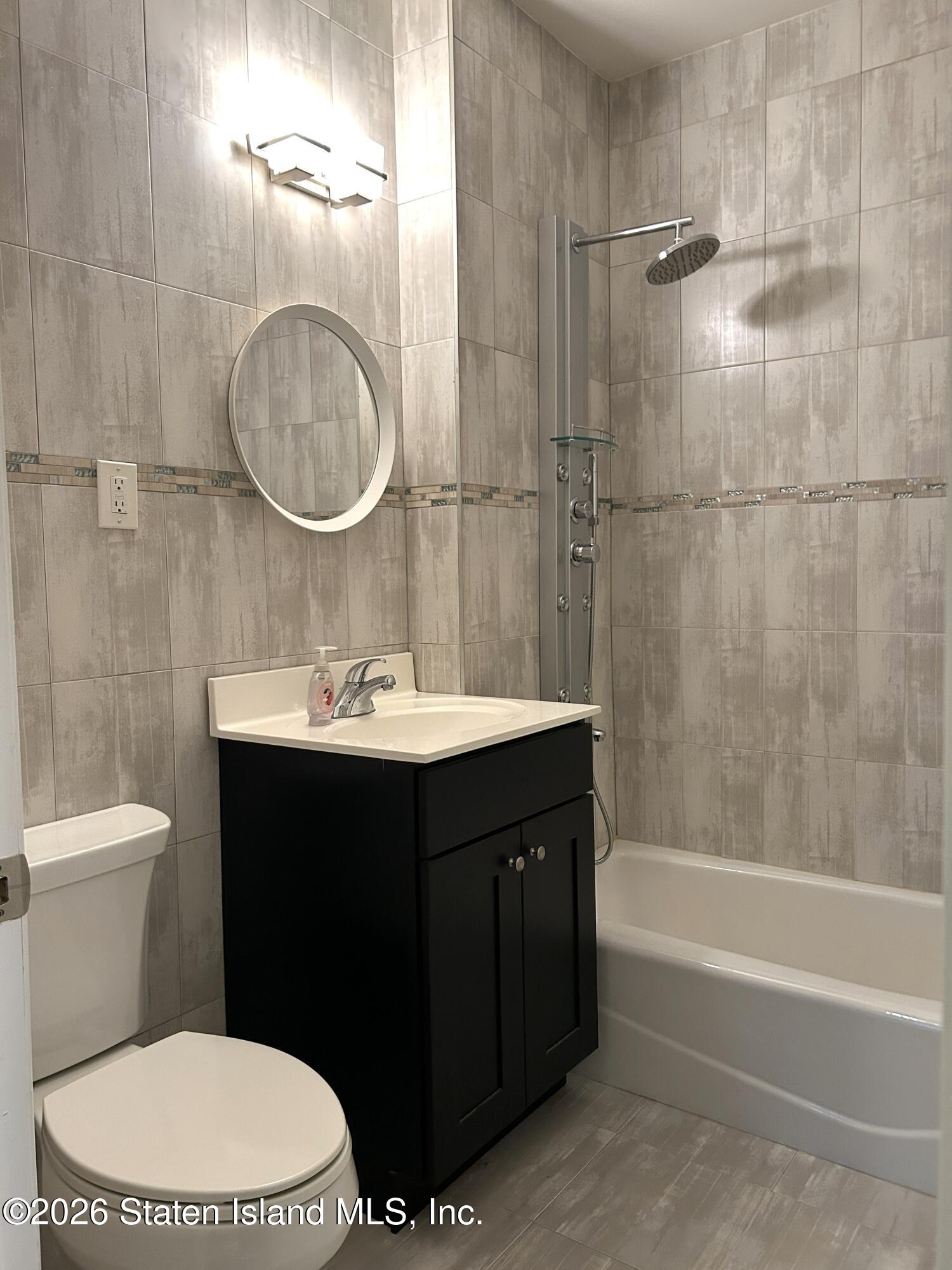 1235 Forest Hill Road, Unit 1G Staten Island, NY 10314 - Photo 7 of 11 a bathroom with a sink a toilet and a mirror