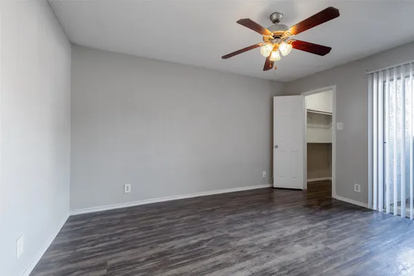 an empty room with wooden floor and a ceiling fan
