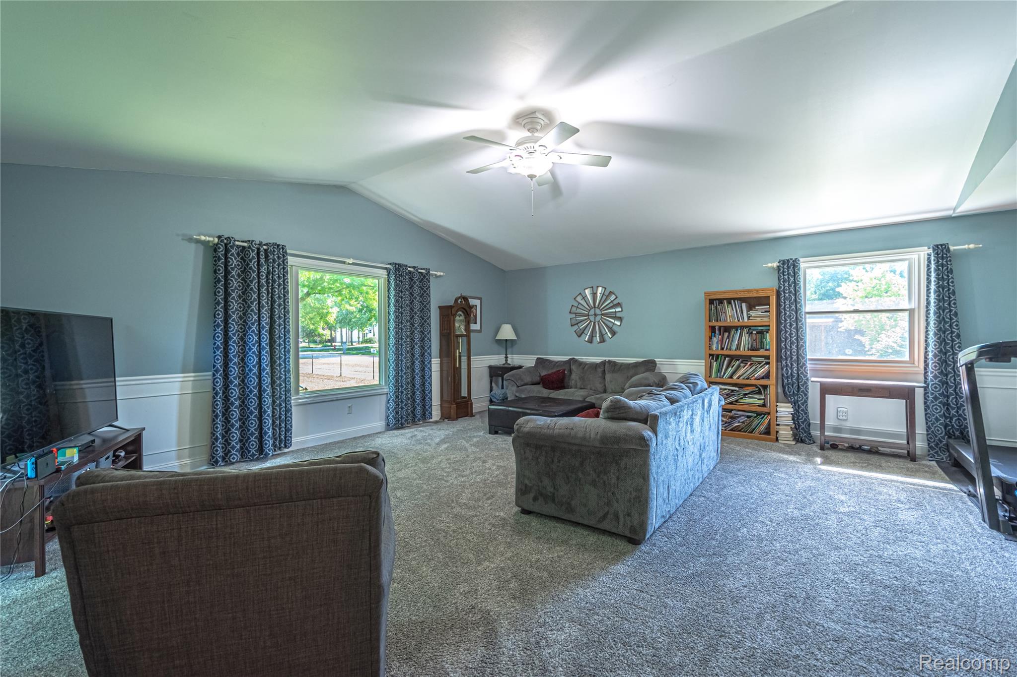 3241 Simpson Road Fort Gratiot, MI 48059 - Photo 16 of 27 Spacious living area featuring a vaulted ceiling with a ceiling fan, light blue wall paint, and white wainscoting