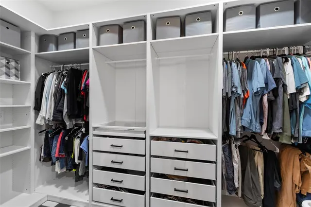 a view of walk in closet with clothes and shoes