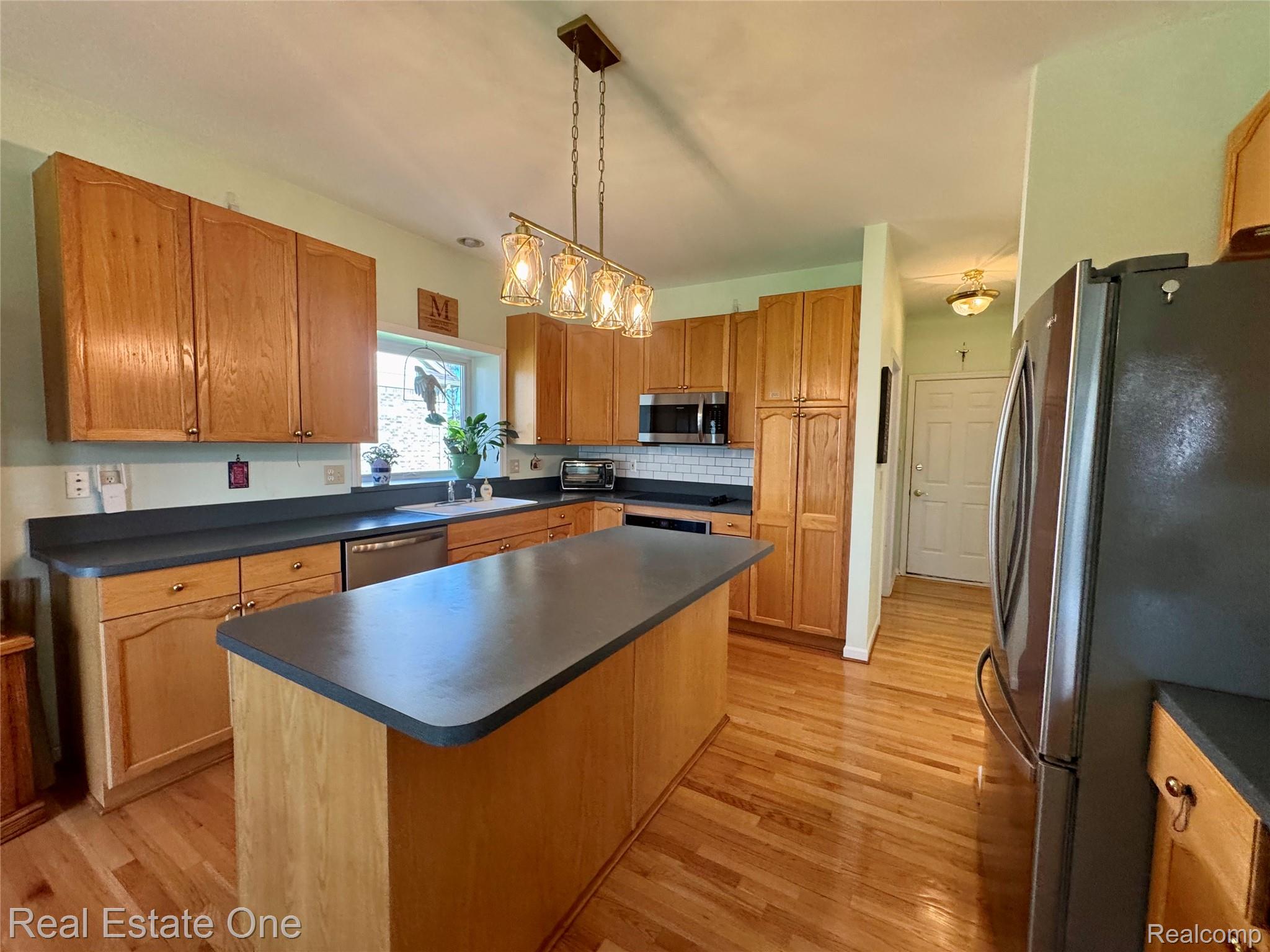 1668 South Shore Drive Rochester, MI 48307 - Photo 9 of 27 Kitchen with stainless steel appliances, a kitchen island, light wood-style flooring, dark countertops, and wood finish cabinets