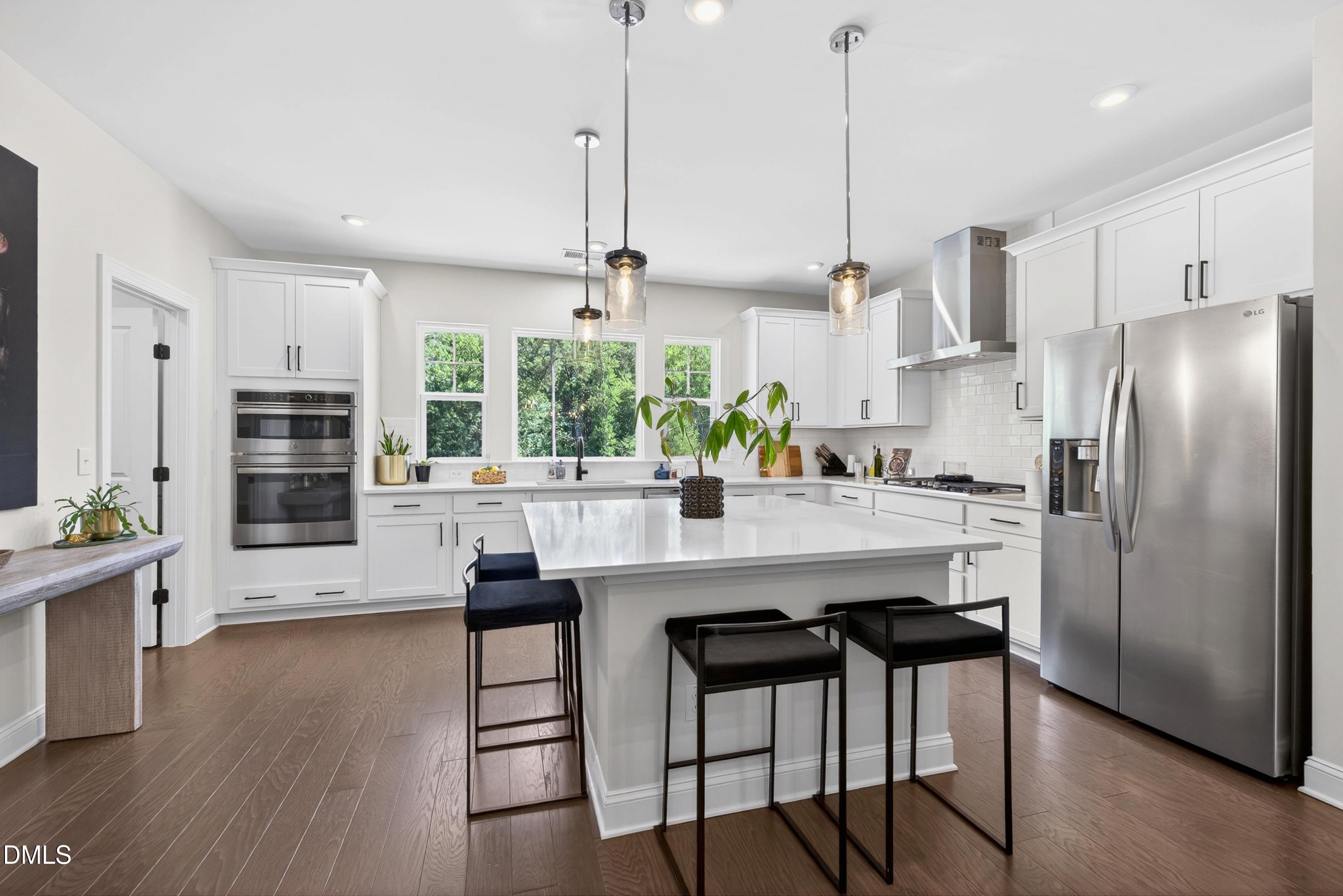1063 Danvers Loop Apex, NC 27523 - Photo 19 of 67 a kitchen with stainless steel appliances kitchen island granite countertop a refrigerator a stove and white cabinets with wooden floor
