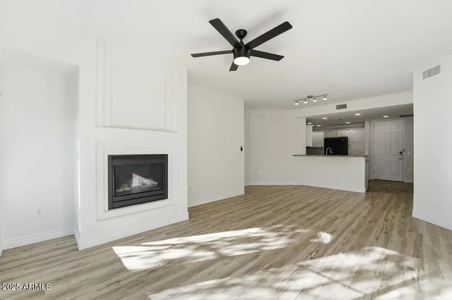 a view of a livingroom with a fireplace a ceiling fan and wooden floor
