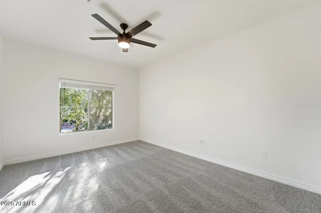 an empty room with windows and ceiling fan