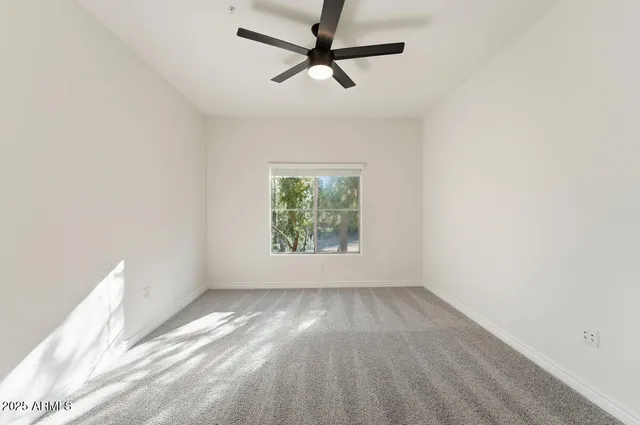 an empty room with a window and a fan