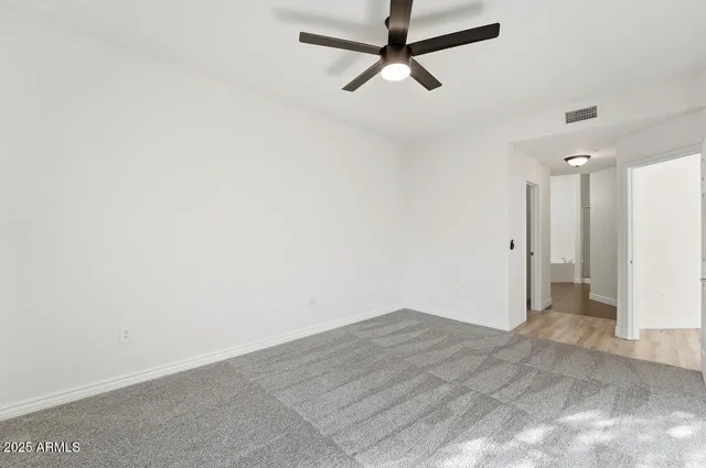 an empty room with closet and a ceiling fan