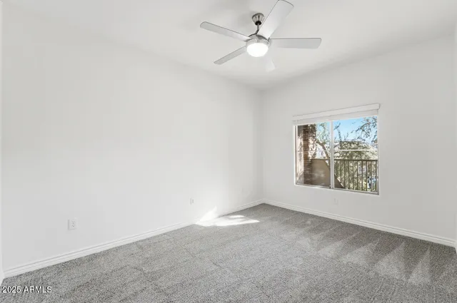 an empty room with a window and a fan