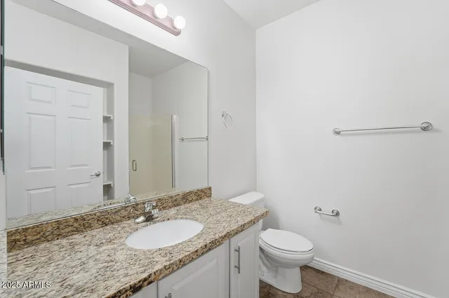 a bathroom with a granite countertop sink a toilet and a mirror