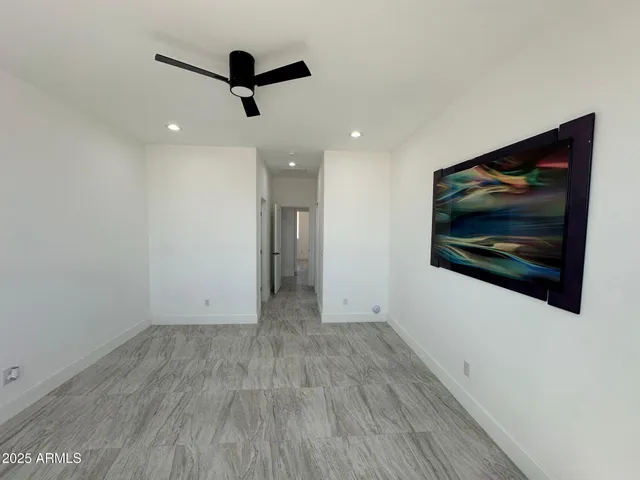 a view of empty room with wooden floor and fan