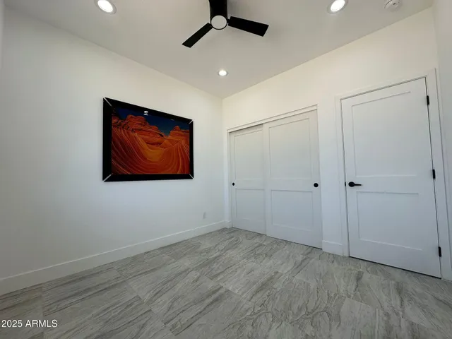 an empty room with wooden floor ceiling fan and windows