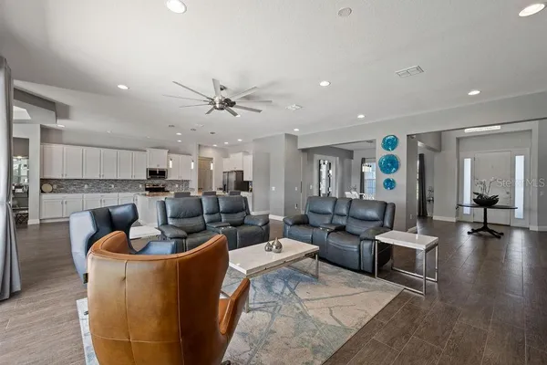 a kitchen with stainless steel appliances kitchen island granite countertop a stove a sink a refrigerator and white cabinets with wooden floor