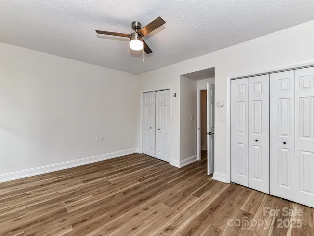 an empty room with wooden floor closet and windows