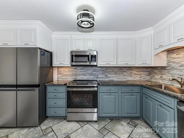 a kitchen with granite countertop a stove top oven microwave and cabinets