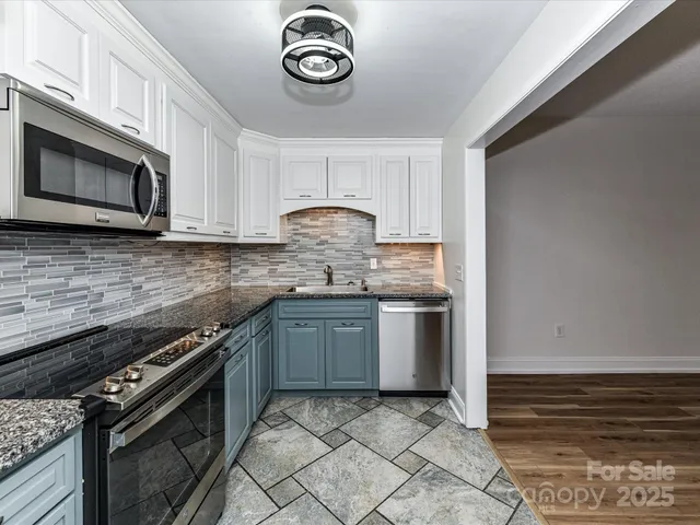 a kitchen with granite countertop a stove top oven microwave and cabinets