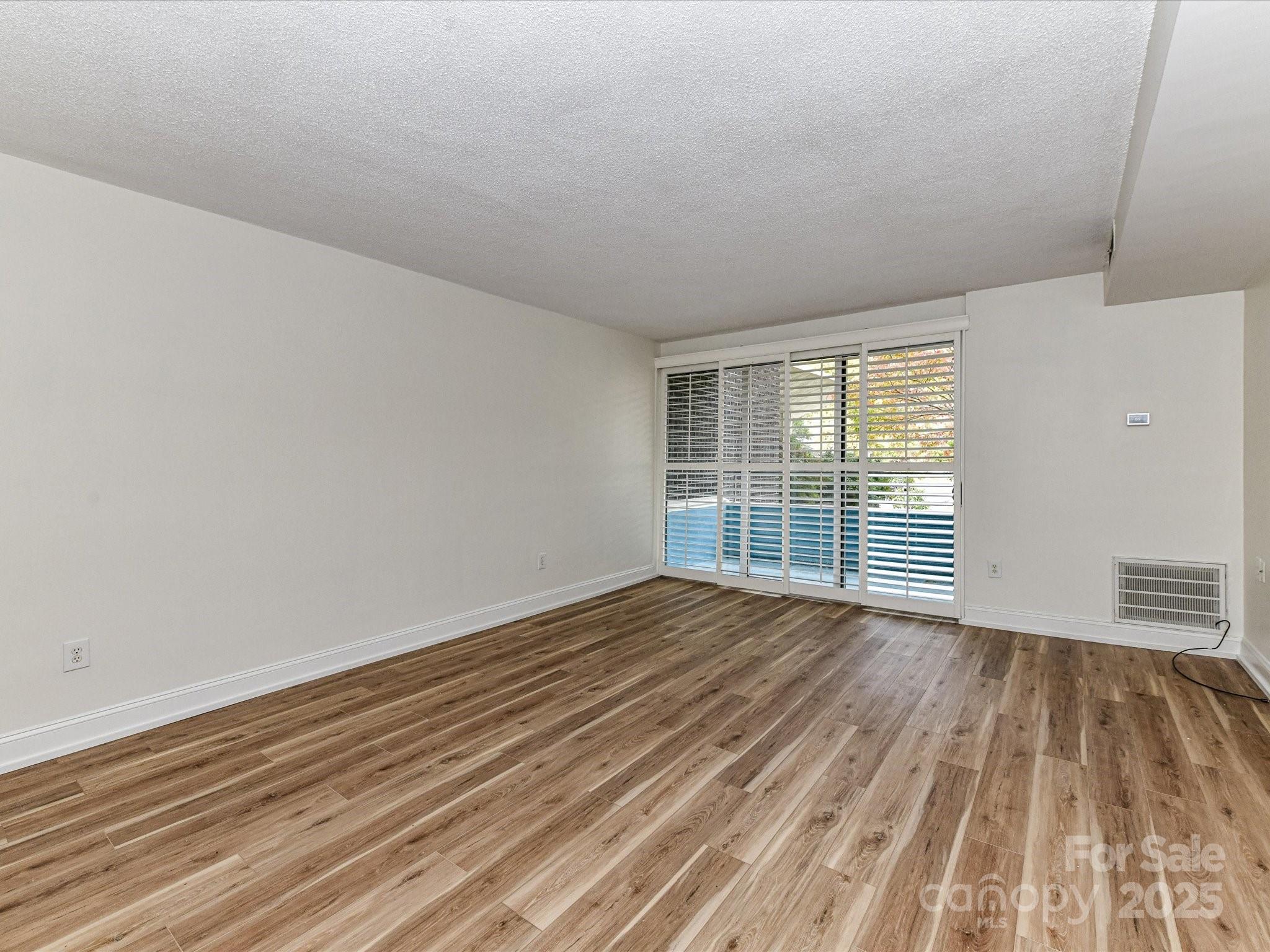 1300 Reece Road, Unit 111 Charlotte, NC 28209 - Photo 9 of 29 a view of an empty room with wooden floor and a window