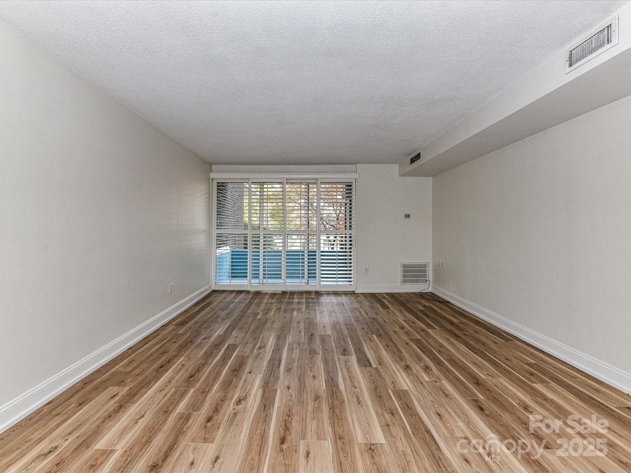 1300 Reece Road, Unit 111 Charlotte, NC 28209 - Photo 10 of 29 a view of an empty room with wooden floor and window