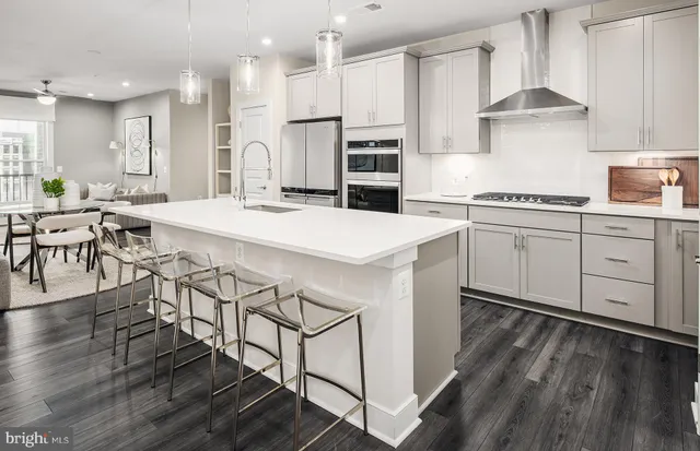 a kitchen with stainless steel appliances kitchen island granite countertop a table chairs and a refrigerator