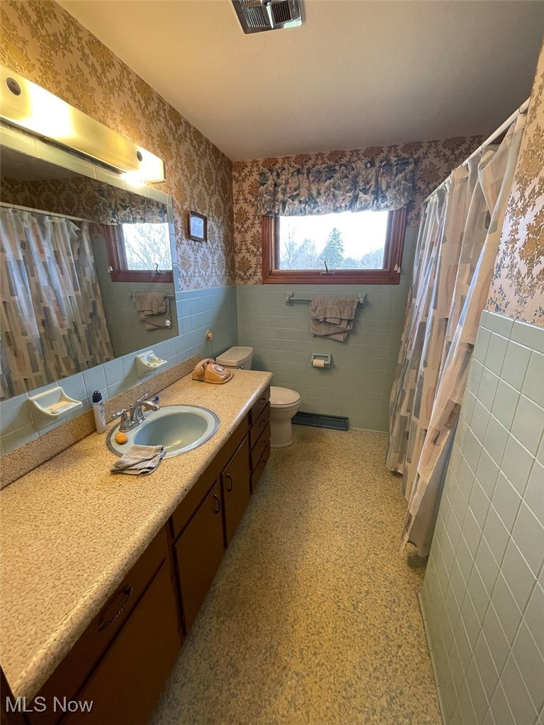 5977 Heather Street Northwest Canton, OH 44708 - Photo 7 of 10 Full bathroom with tile walls, plenty of natural light, wallpapered walls, visible vents, and wainscoting
