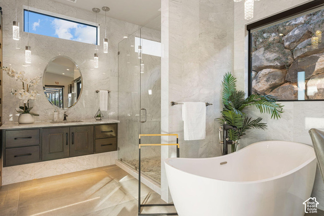 3652 South Cypress Road Hurricane, UT 84737 - Photo 61 of 81 Floating vanity with a stone countertop and an oval mirror, glass-enclosed shower, freestanding soaking tub, and pendant lighting