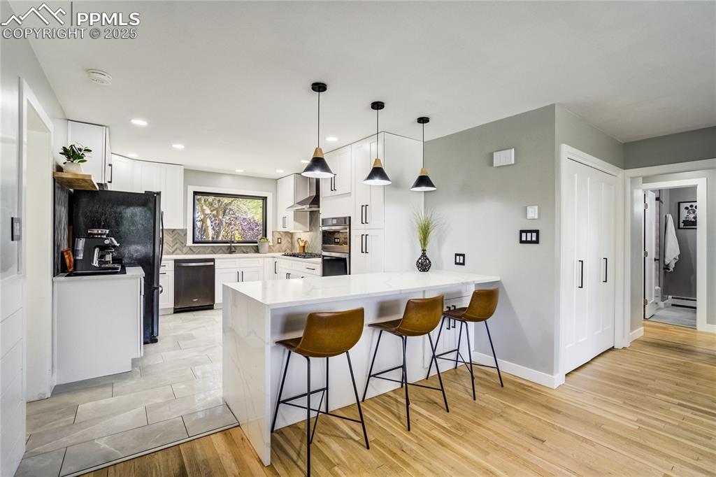 204 Mitchell Avenue Monument, CO 80132 - Photo 14 of 46 a kitchen with stainless steel appliances kitchen island granite countertop a refrigerator a stove and white cabinets with wooden floor