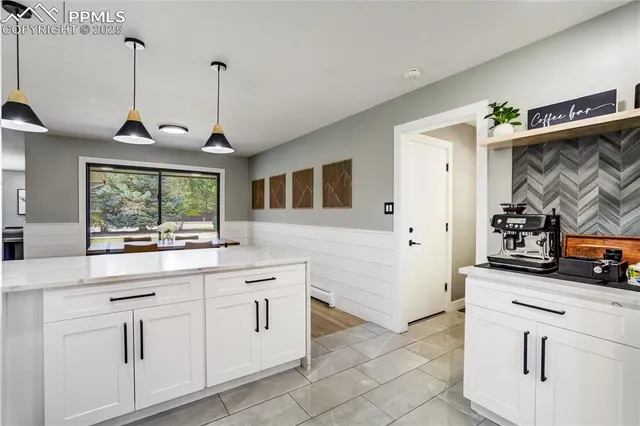 a kitchen with white cabinets and window