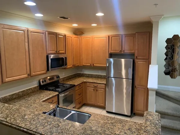 a kitchen with stainless steel appliances granite countertop a refrigerator a stove and a sink with wooden floor