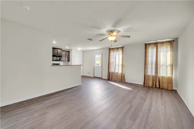 a view of an empty room with window and wooden floor