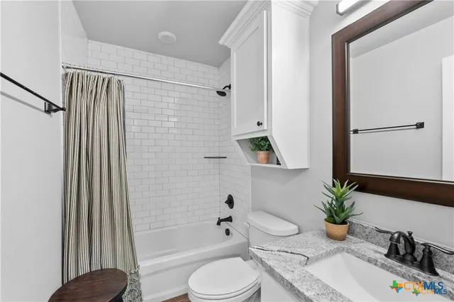 a bathroom with a granite countertop sink a toilet and shower
