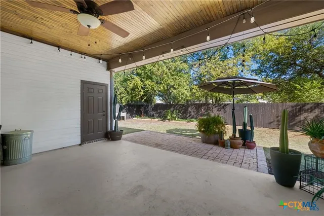 a view of a patio with table and chairs under an umbrella with a small yard