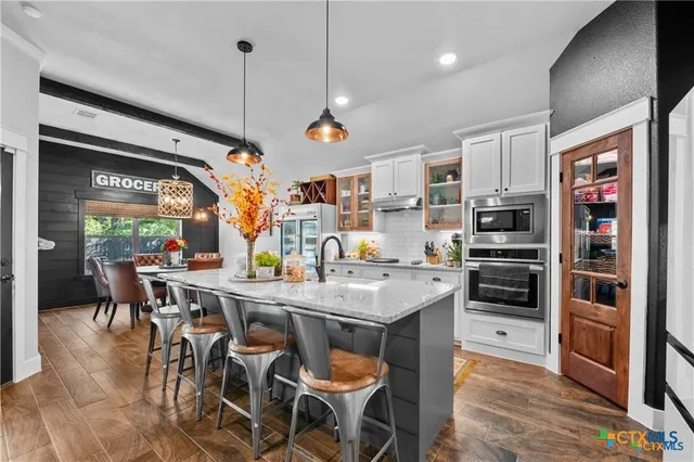 a kitchen with stainless steel appliances granite countertop a stove a sink dishwasher and a refrigerator with wooden floor