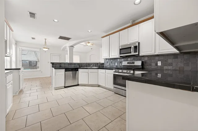 a kitchen with stainless steel appliances granite countertop white cabinets granite counter tops and a window