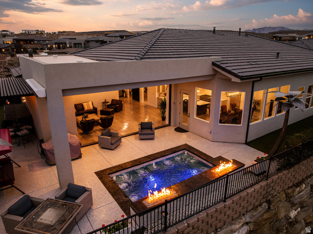 3022 West Sesia Way St. George, UT 84770 - Photo 5 of 52 Back of house at dusk featuring stucco siding, a patio, outdoor lounge area, and a fire pit