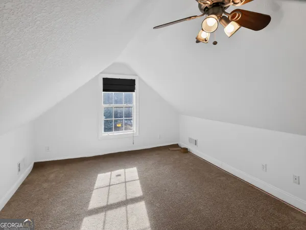 an empty room with a chandelier fan and windows