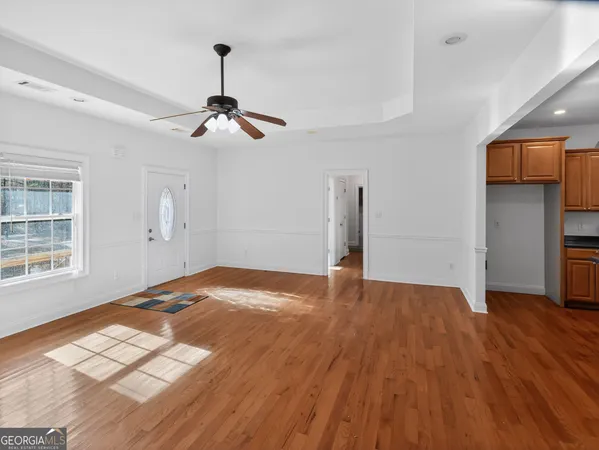 a view of empty room with wooden floor and fan