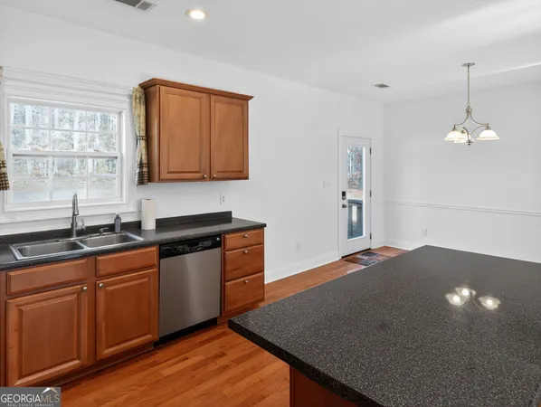 a kitchen with stainless steel appliances granite countertop a sink a stove and a wooden cabinets
