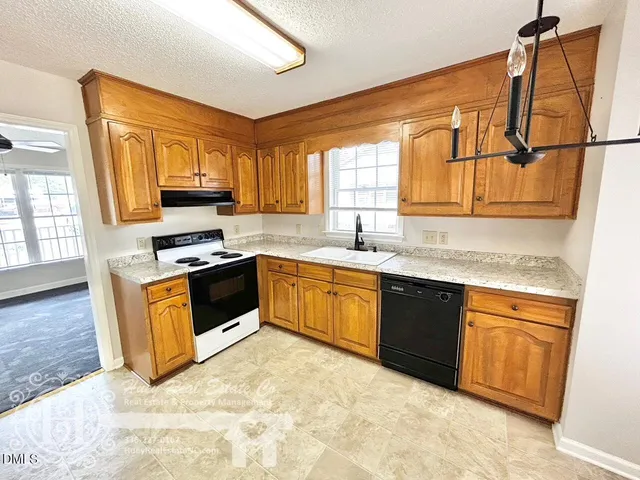 a kitchen with stainless steel appliances granite countertop a sink a stove a refrigerator cabinets and a window
