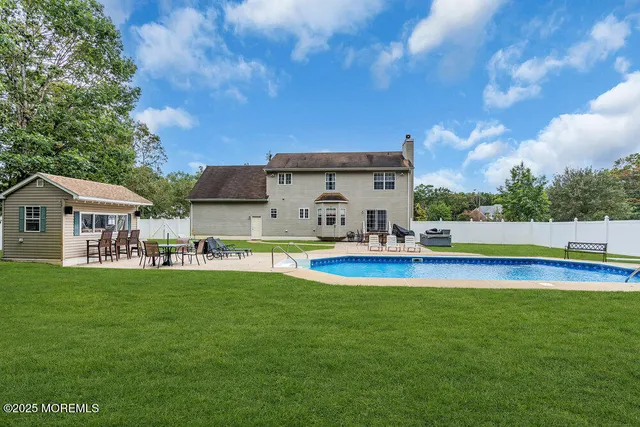 a view of pool with lawn chairs and large trees
