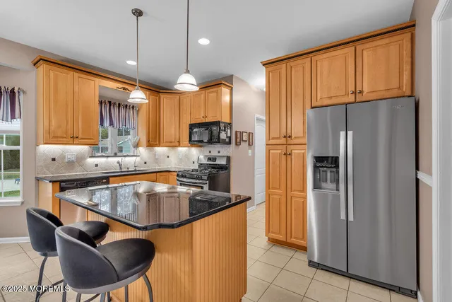 a kitchen with stainless steel appliances granite countertop a refrigerator a sink and a stove