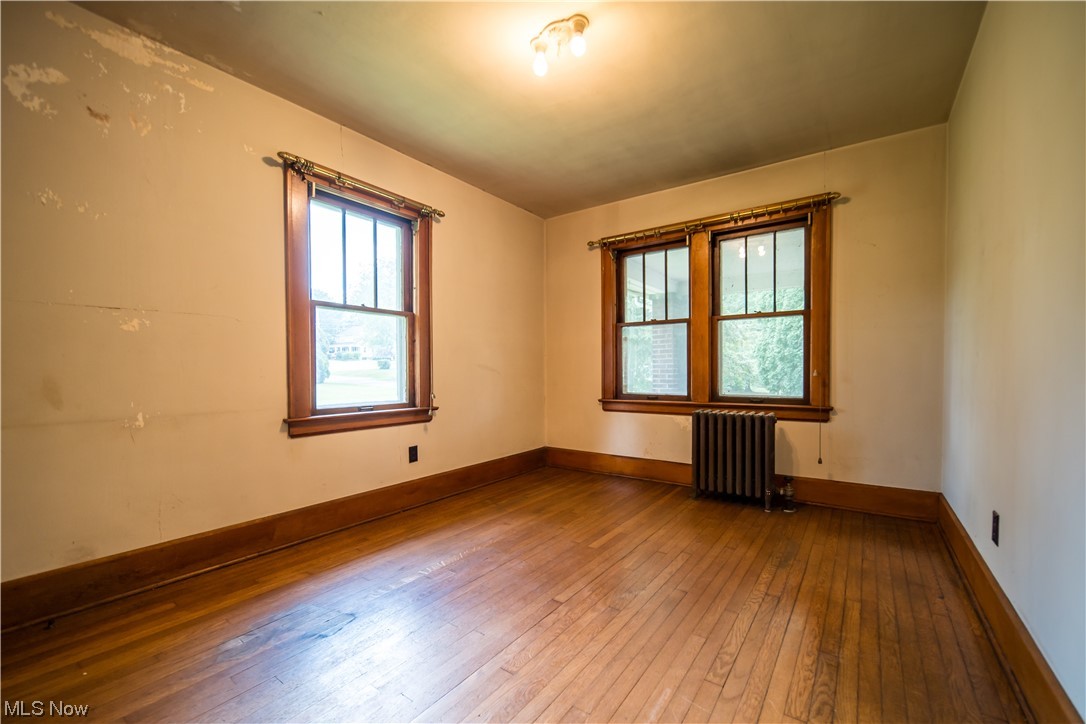 3023 Woodland Road Akron, OH 44312 - Photo 14 of 30 Wood floored spare room with radiator heating unit