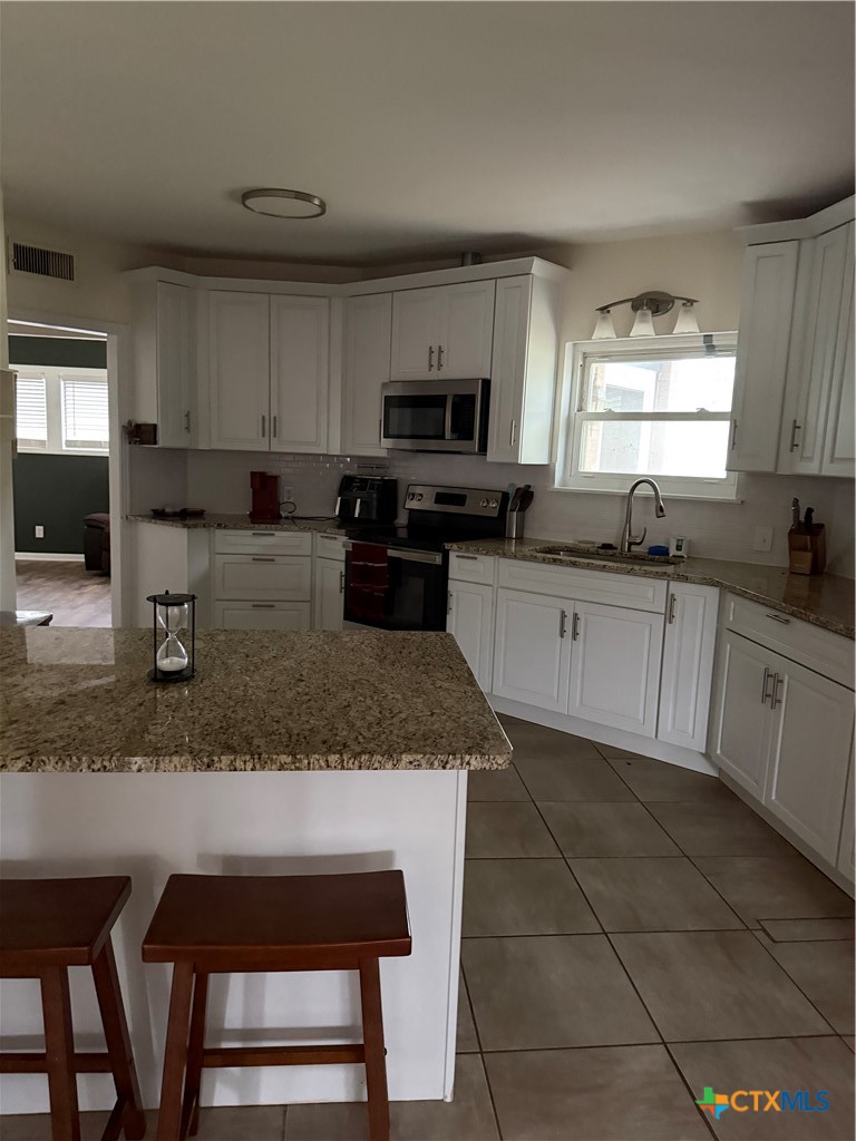 202 Bonham Street Port Lavaca, TX 77979 - Photo 7 of 11 a kitchen with granite countertop a sink a stove a microwave and cabinets