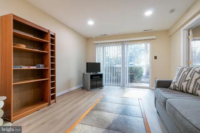 a living room with furniture a flat screen tv and a floor to ceiling window