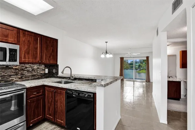 a kitchen with granite countertop a sink stove and cabinets